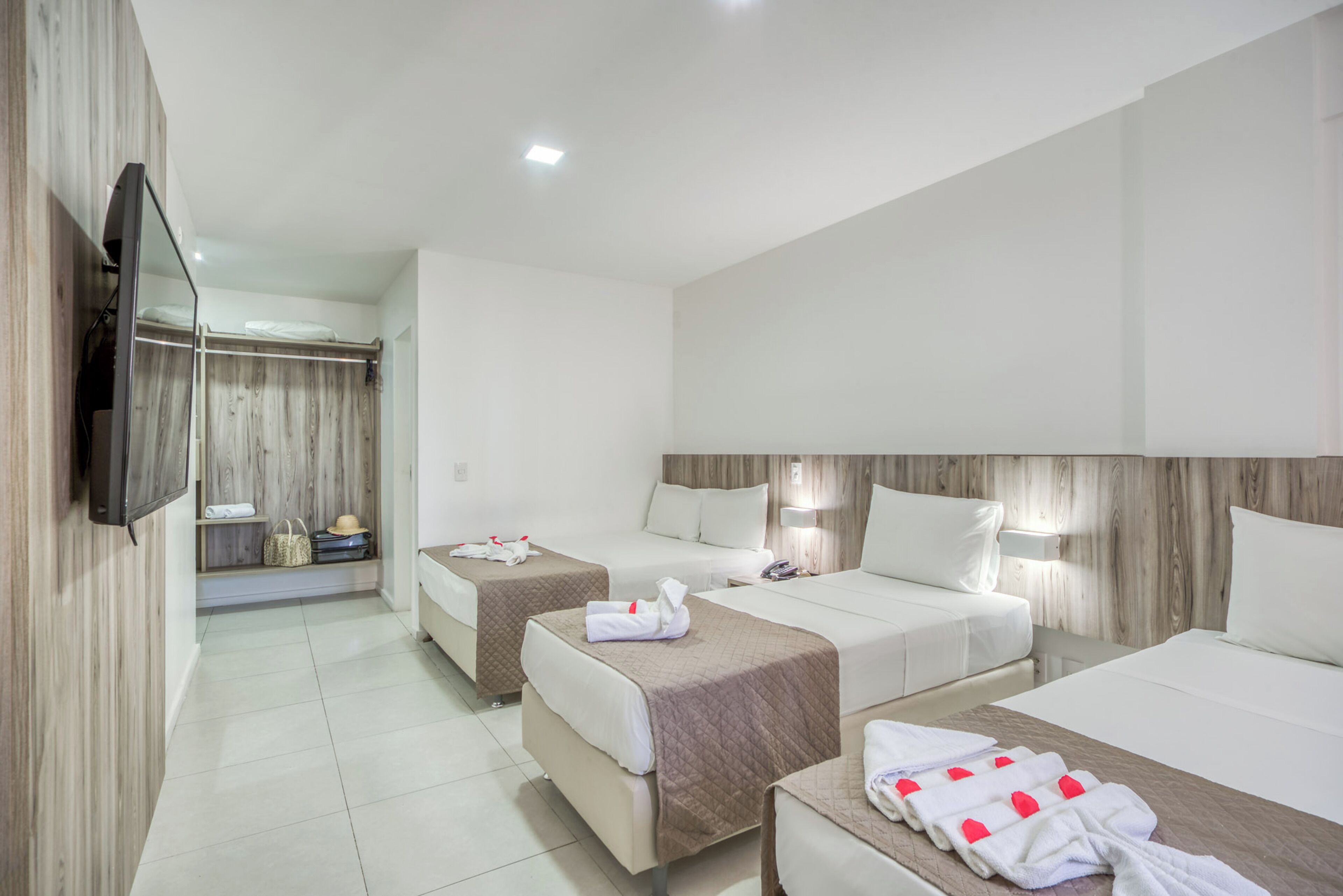 A hotel room with two beds, a TV, and a wooden wardrobe.