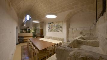 A rustic stone interior with a dining area, kitchen, and staircase.