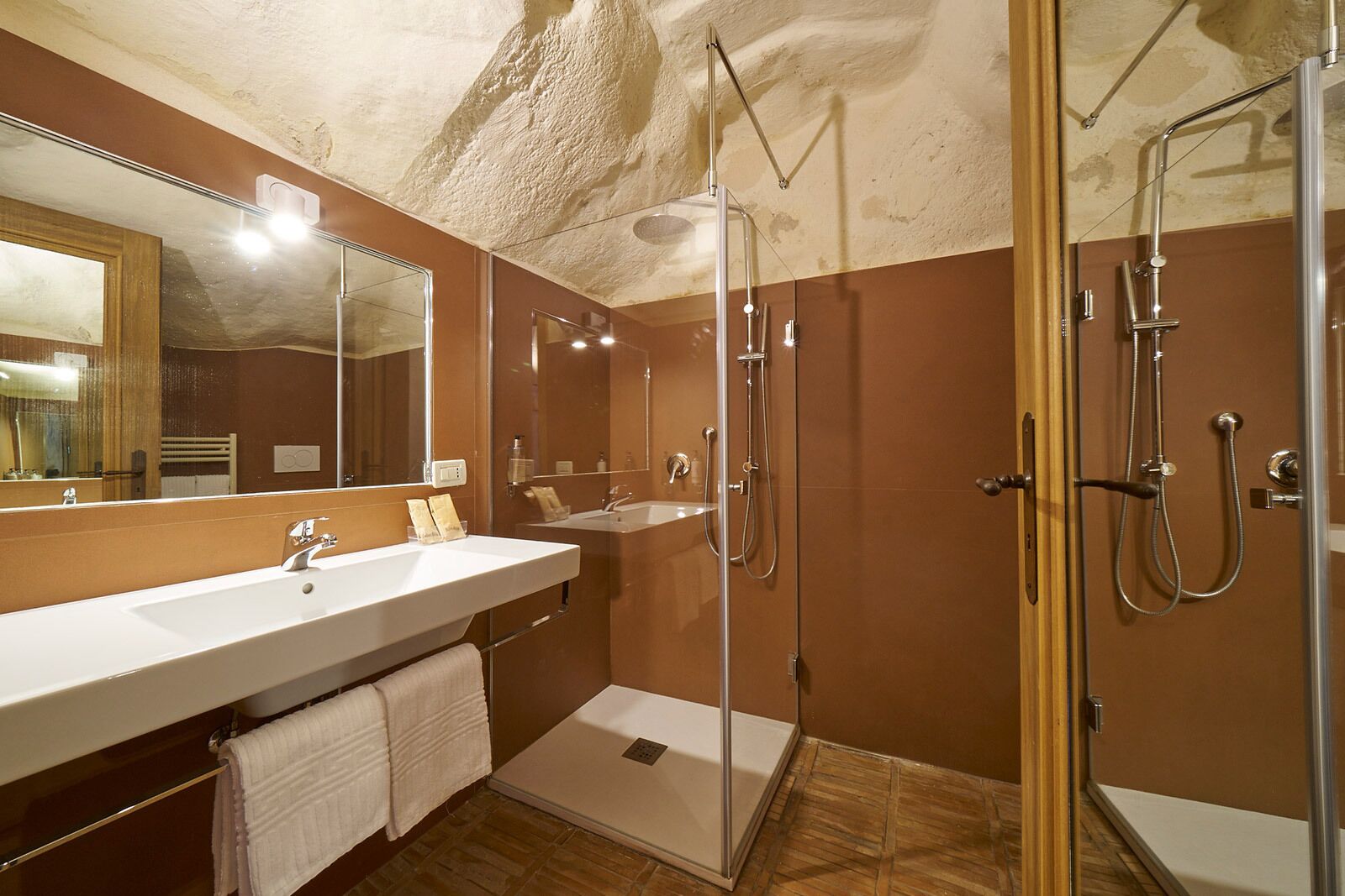 Un baño moderno con un espejo grande, dos lavamanos, una ducha y zona de ducha con mampara de vidrio.
