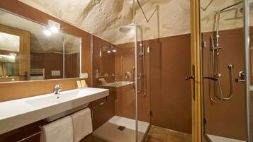 Un baño moderno con un espejo grande, dos lavamanos, una ducha y zona de ducha con mampara de vidrio.