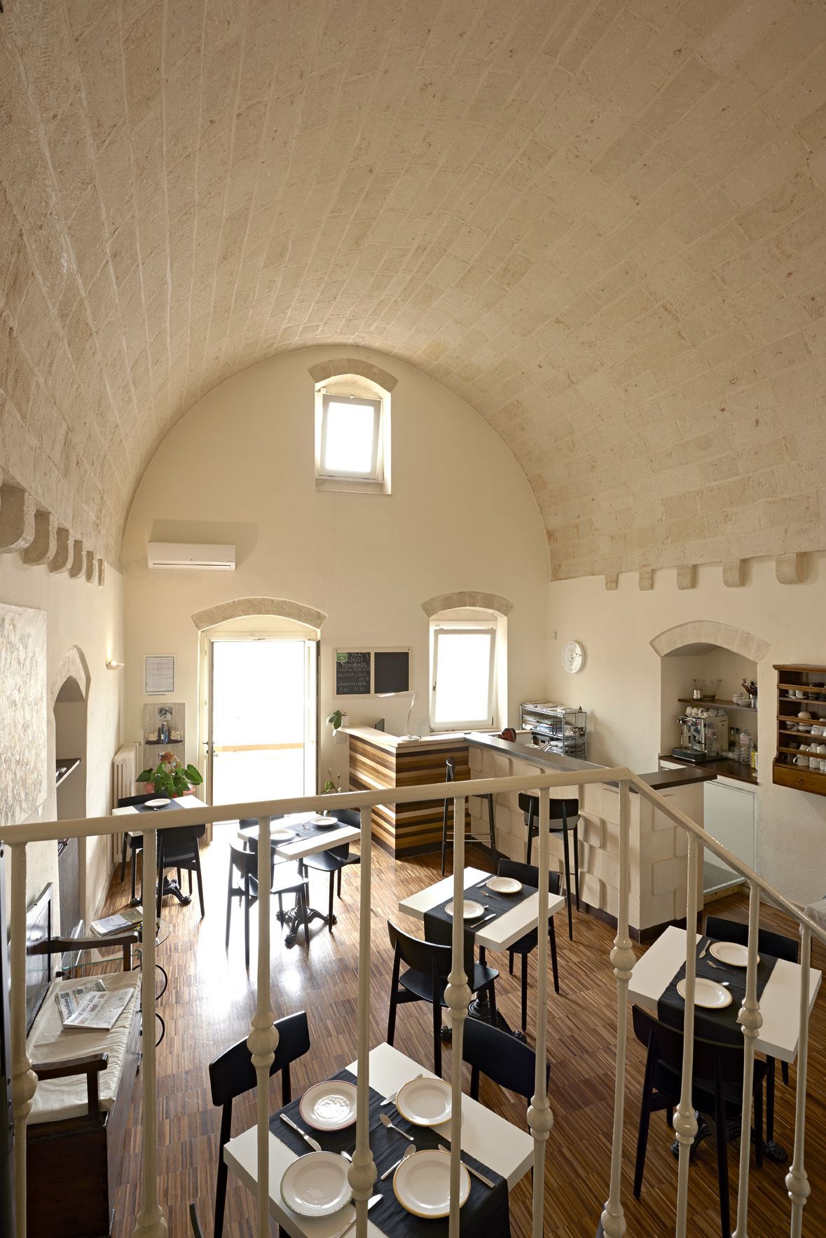 Un comedor espacioso con techos altos y ventanas arqueadas, con varias mesas y sillas.