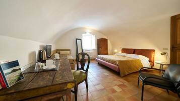 Una habitación acogedora con una mesa de madera, una cama, una silla y una mesita de noche con una lámpara.