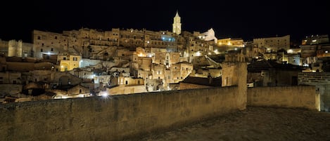 Eine historische Stadt bei Nacht mit beleuchteten Gebäuden und einem markanten Turm.