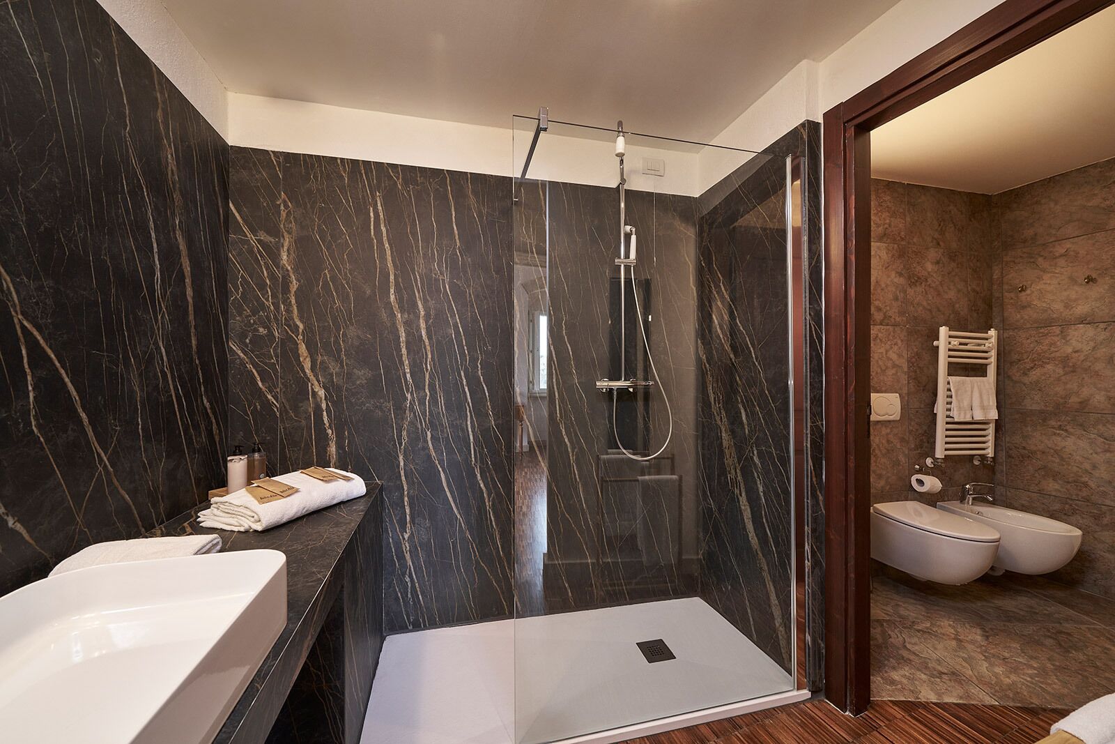 Un baño moderno con ducha envuelta en vidrio, un lavamanos grande y dos bidés.