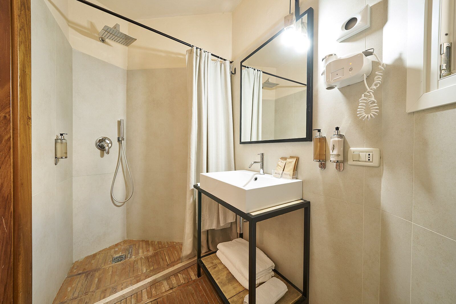 Een moderne badkamer met een douche, een wastafel en een spiegel.