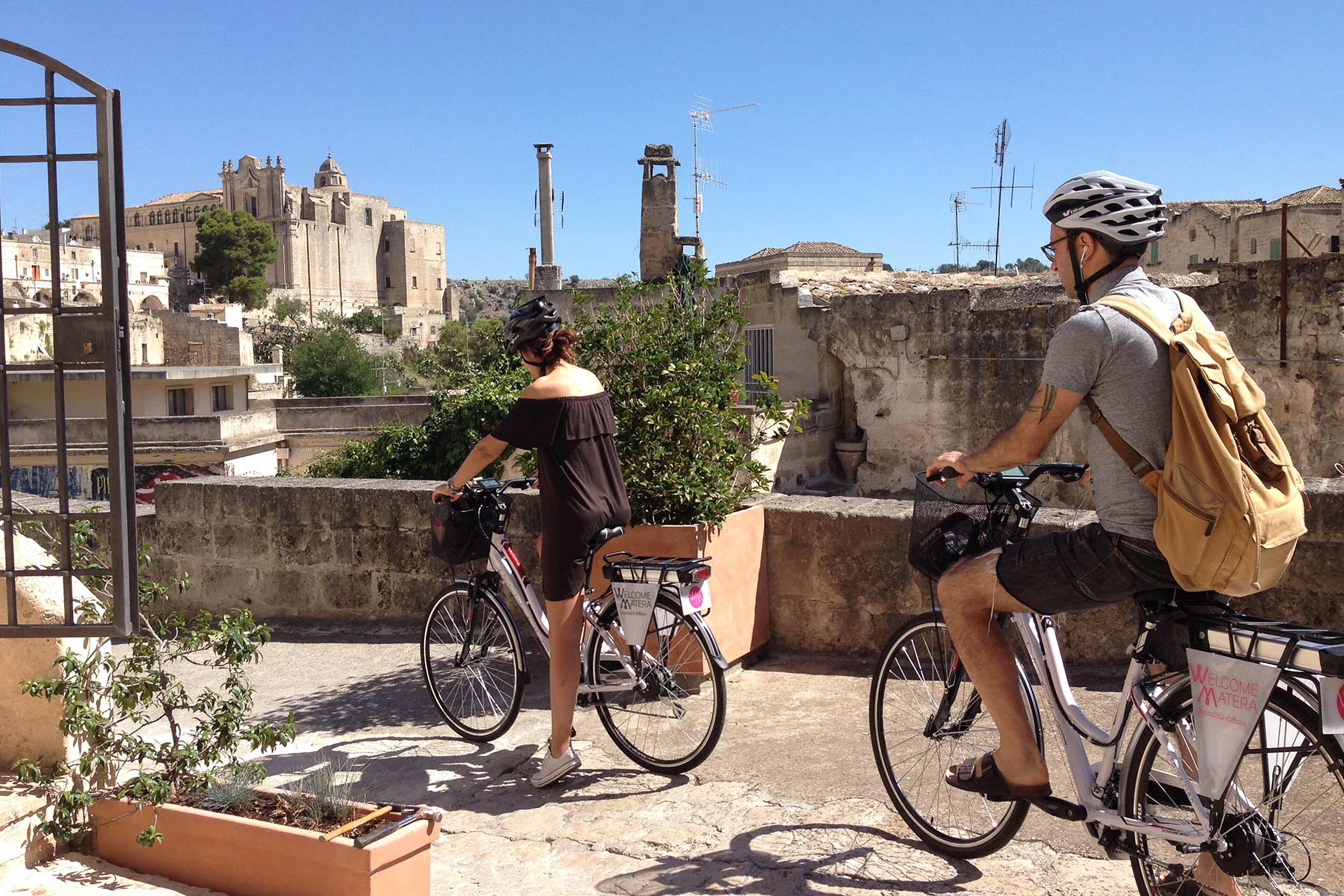 Two people on bicycles with a historic building in the background.