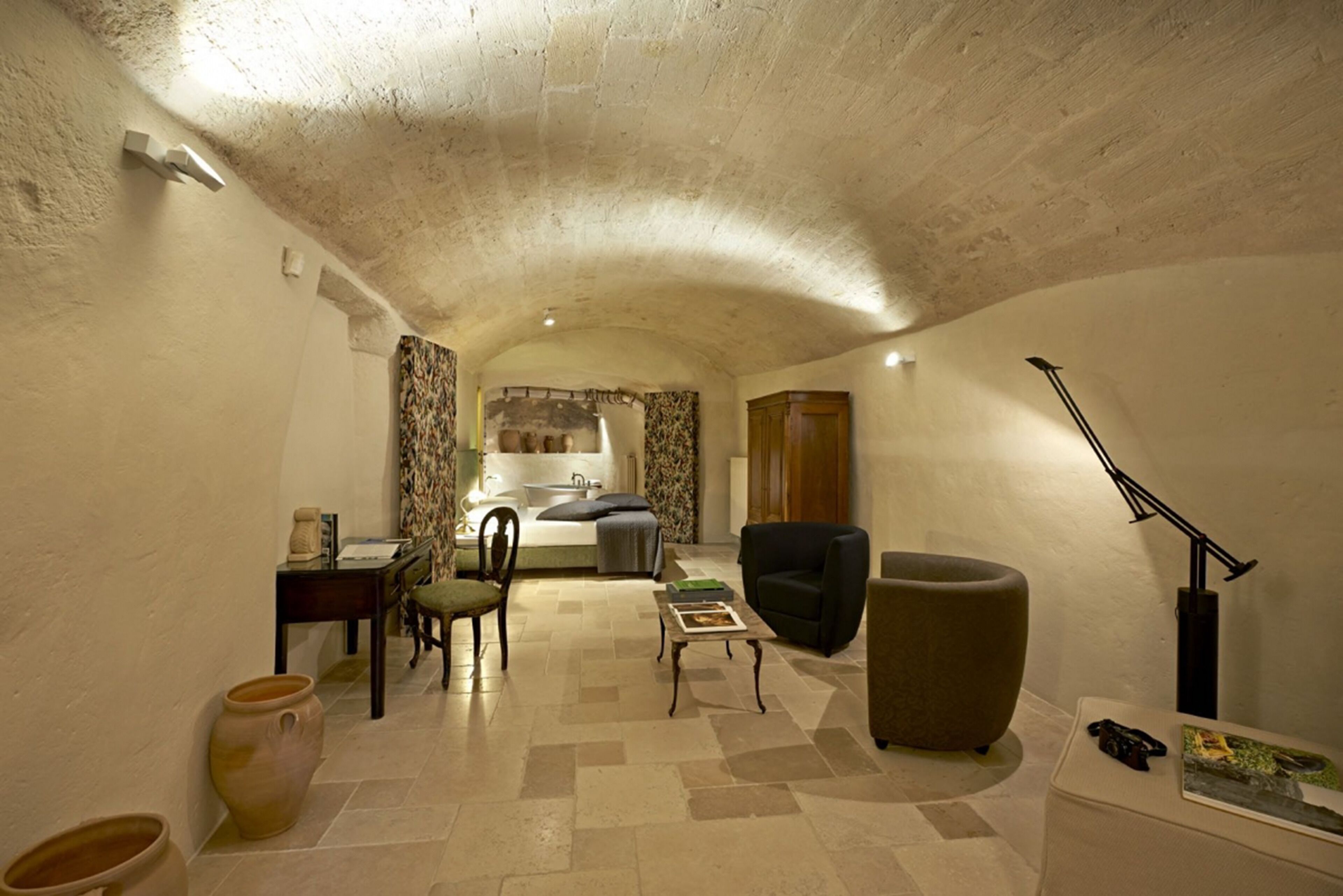 A cozy, well-lit room with a bed, a desk, a chair, and a sofa.