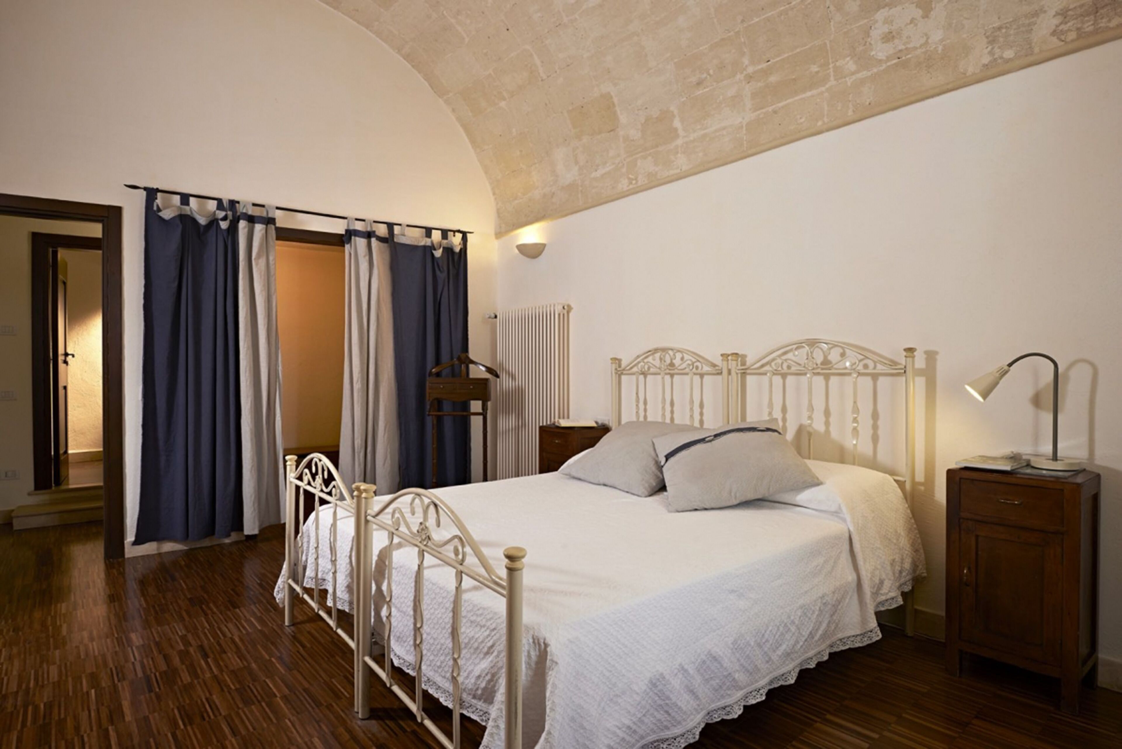 A bedroom with a bed, wooden floor, and a stone ceiling.