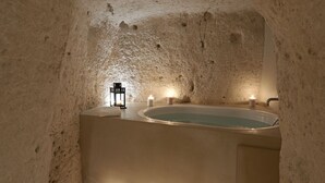 An underground bathroom with a bathtub, a sink, and a lantern. - Fra i Sassi - Residence (Matera)