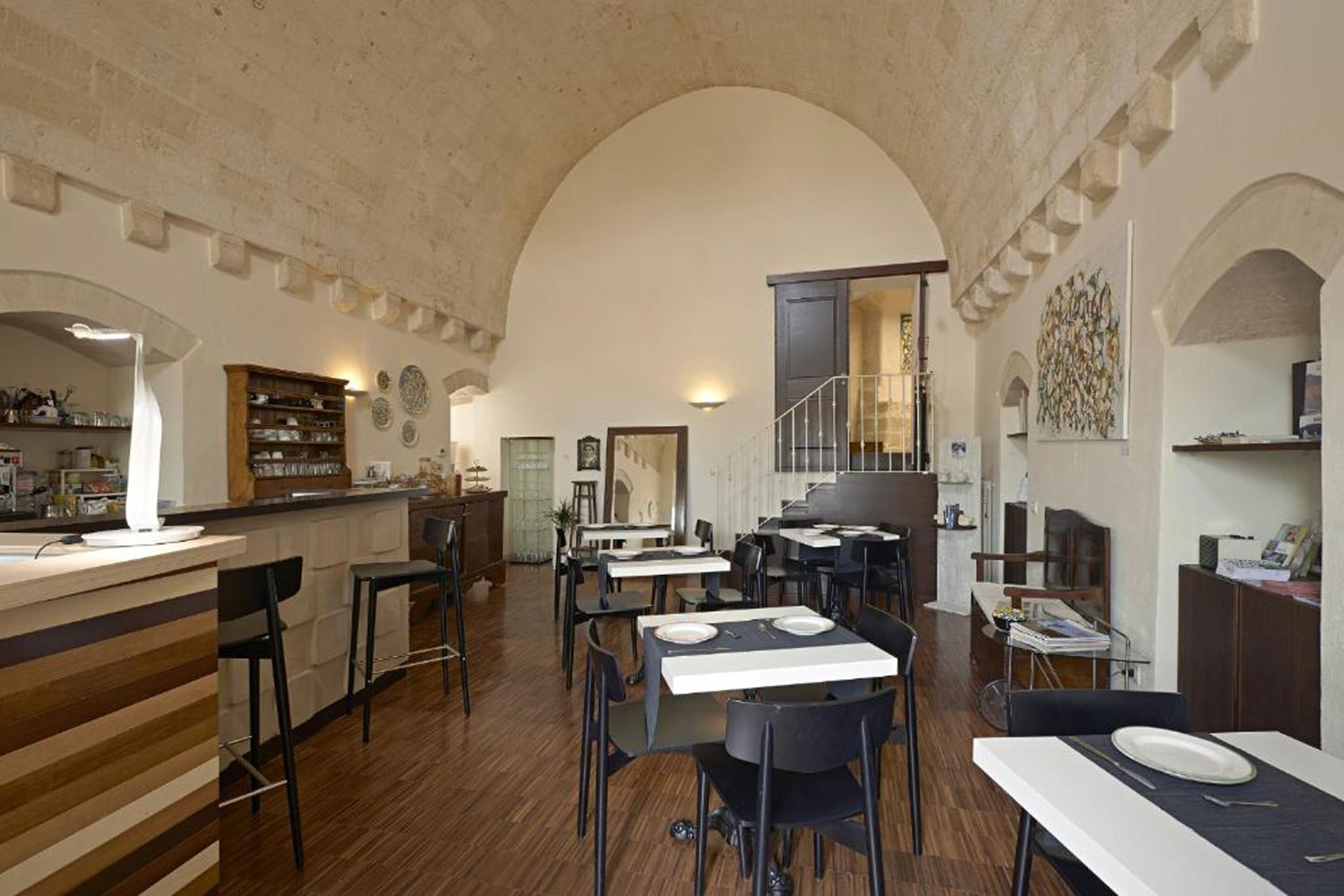 A restaurant with high arched ceilings, wooden bar counter, and multiple dining tables with chairs.