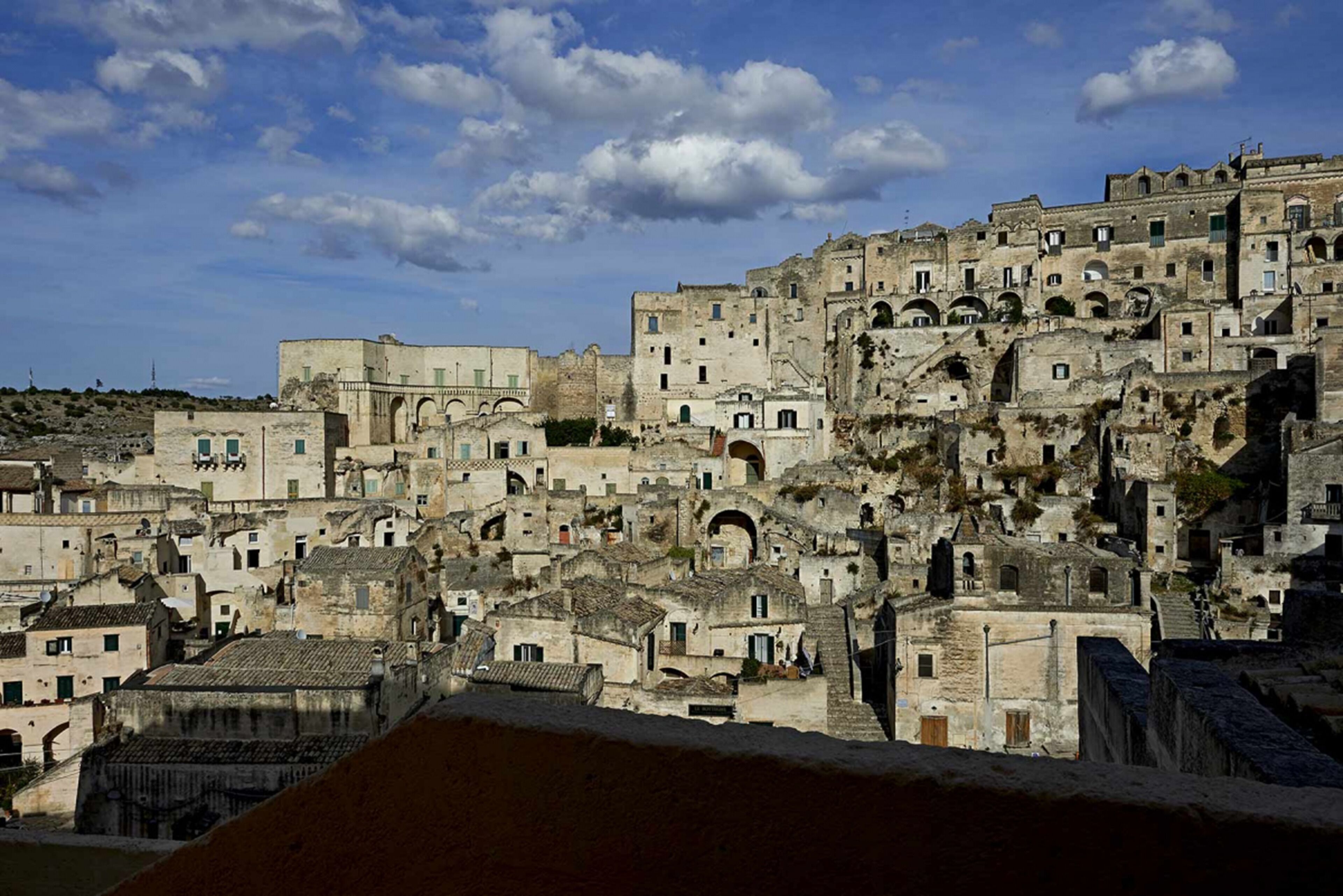 A densely packed hillside town with historic stone buildings, narrow streets, and a prominent church with a bell tower.