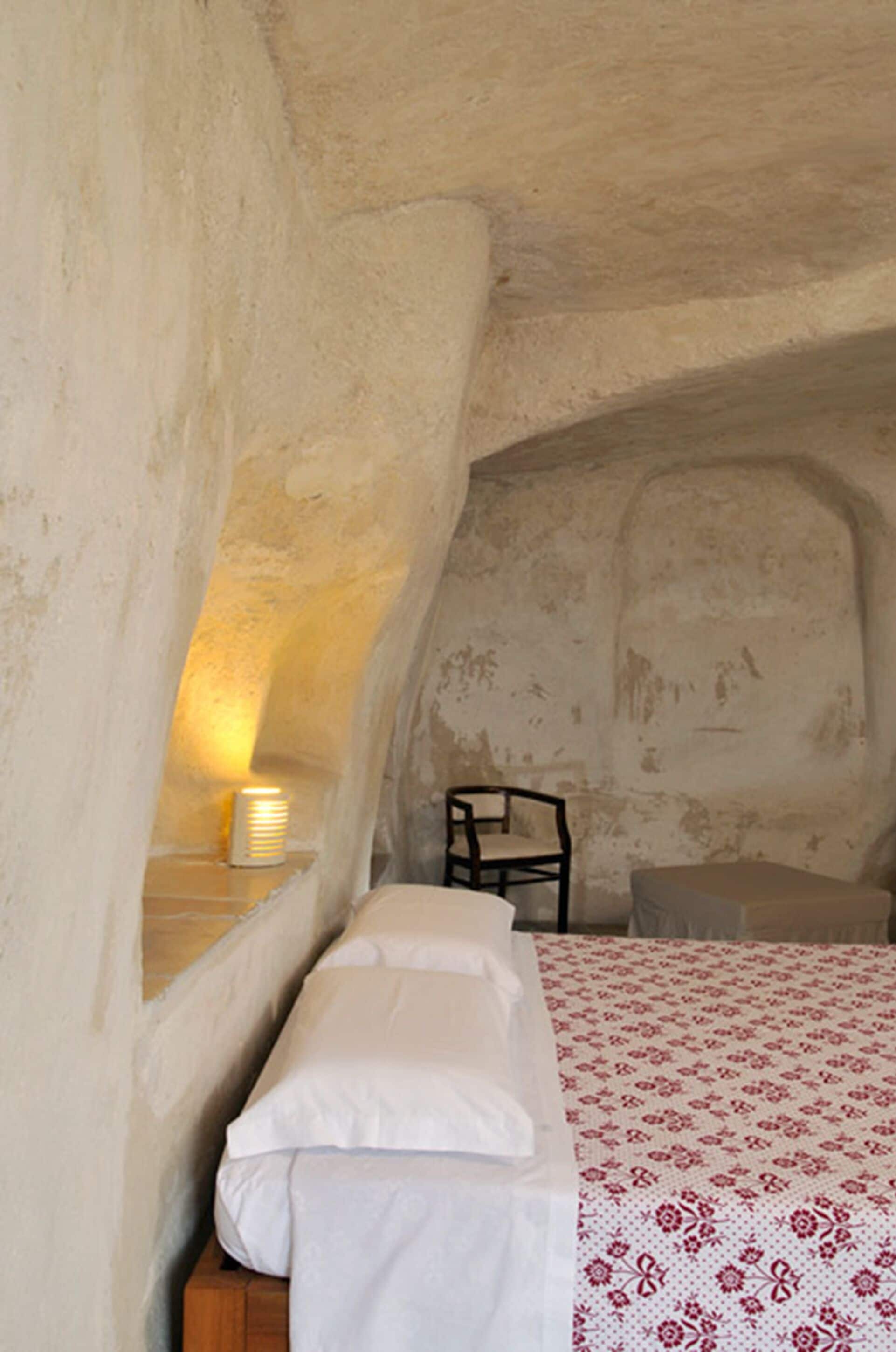 Una habitación acogedora y rústica con una cama, una silla y una mesita de noche con lámpara.