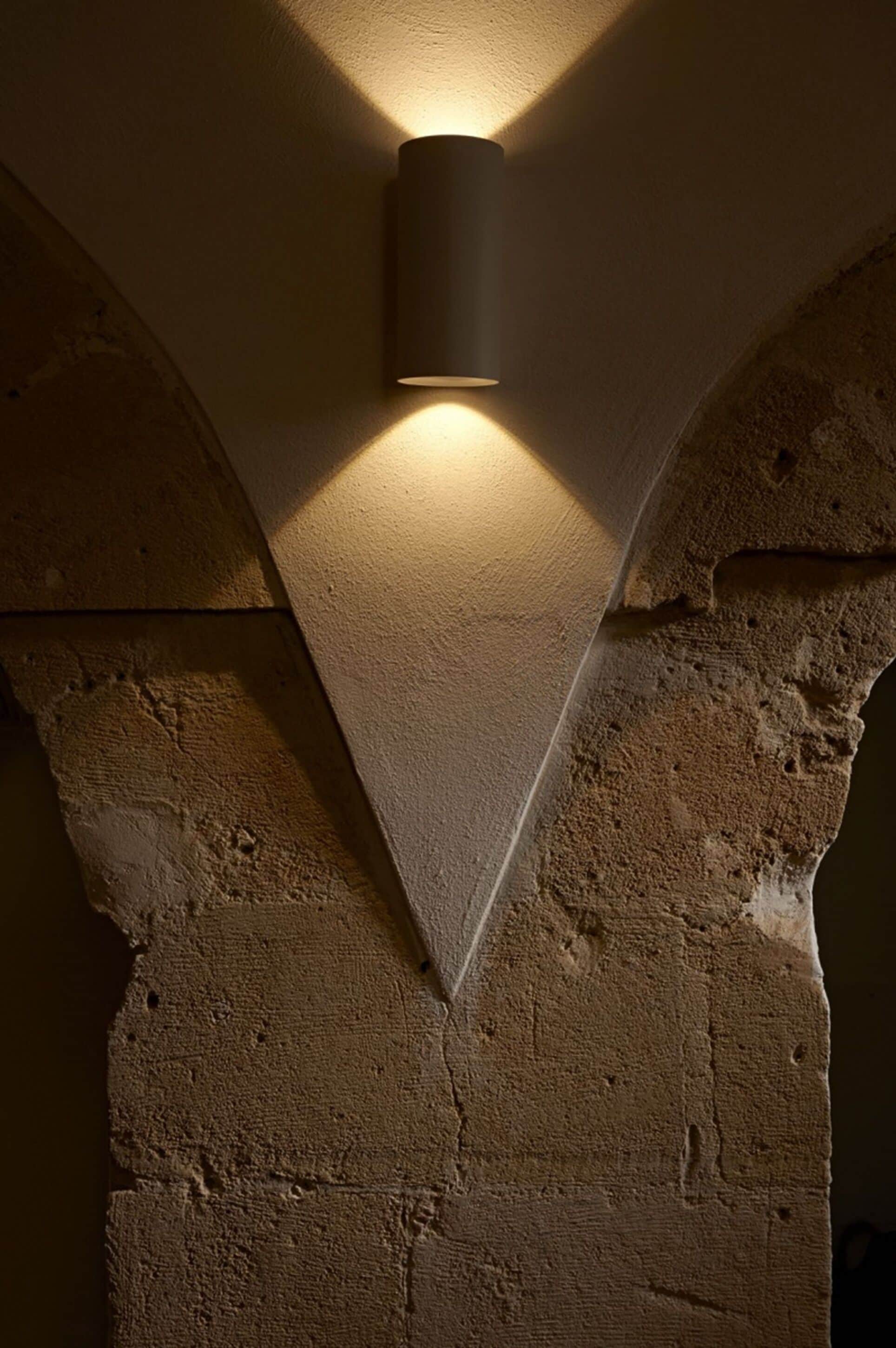 A stone wall with a cylindrical light fixture mounted on it.
