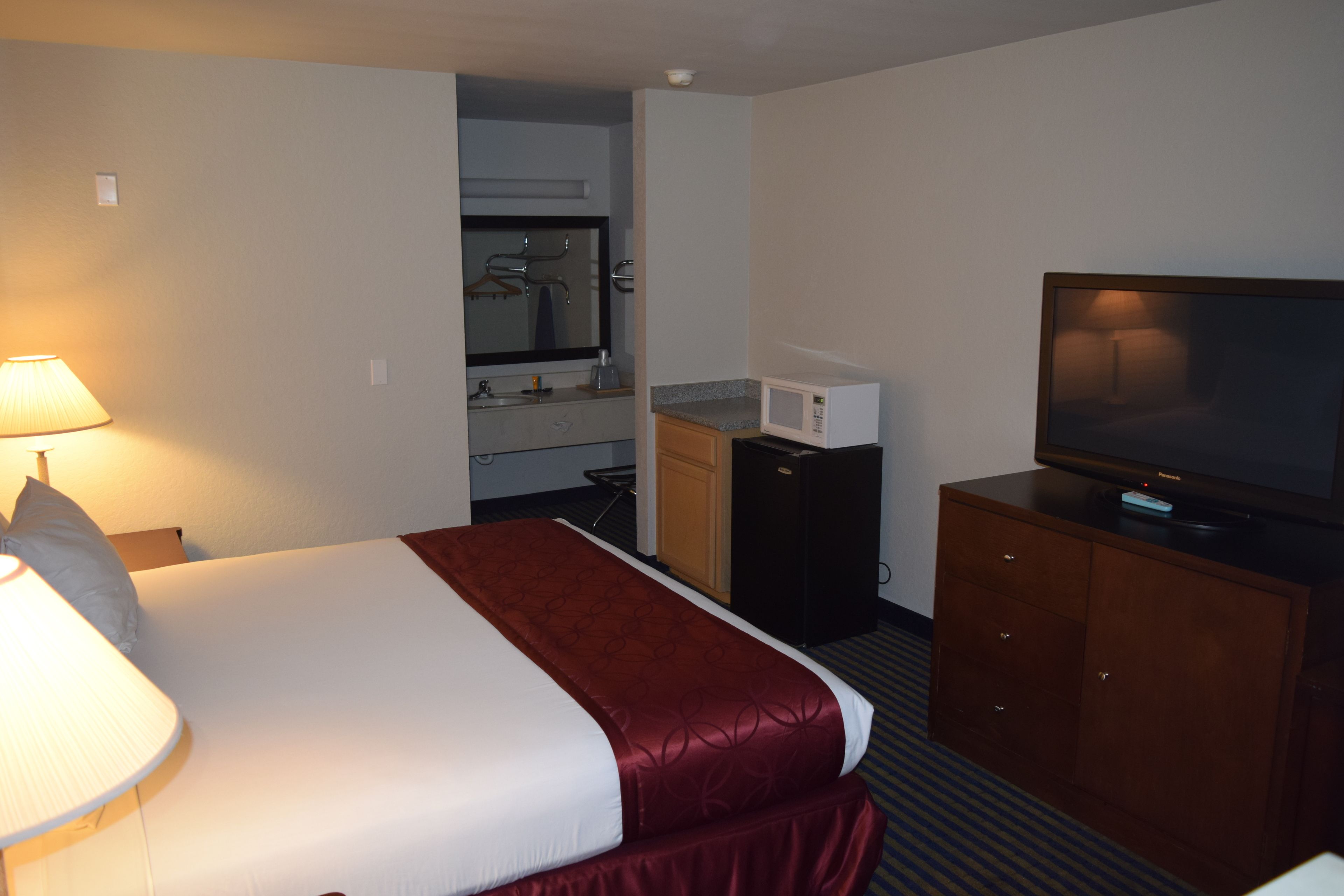 Ein Hotelzimmer mit Bett, Fernseher, Mikrowelle und einer kleinen Küchenzeile.