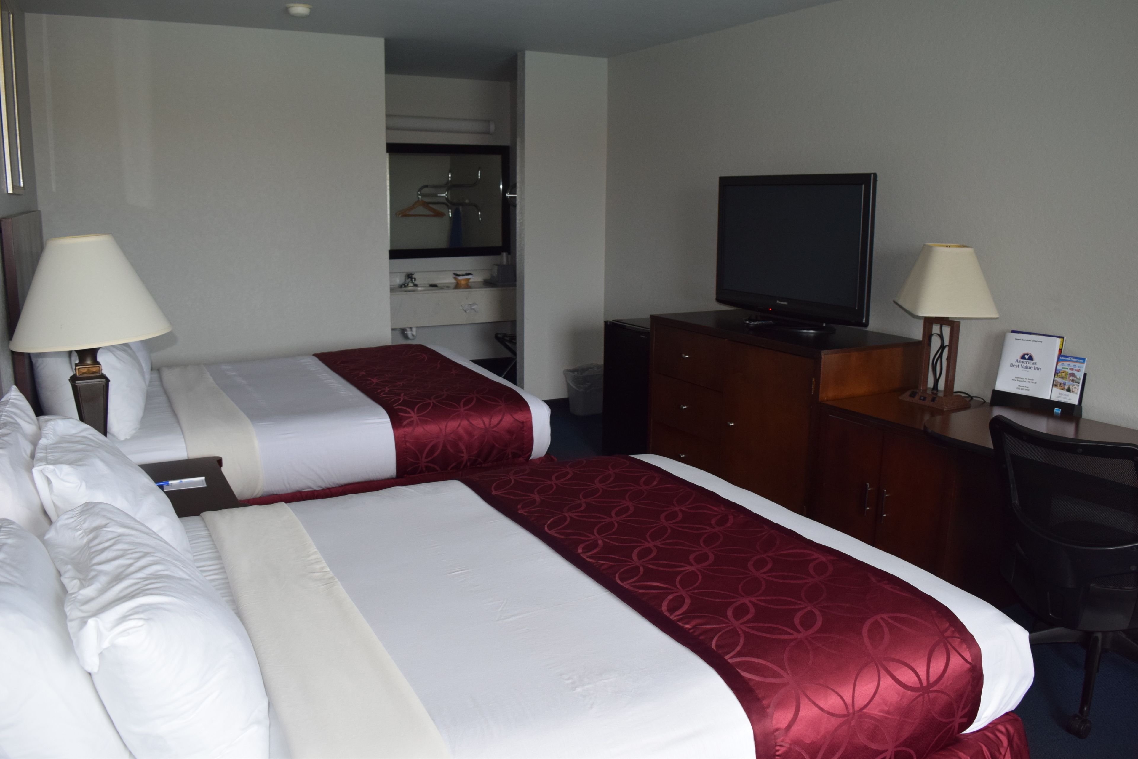 A hotel room with two beds, a TV, a desk, and a wardrobe.