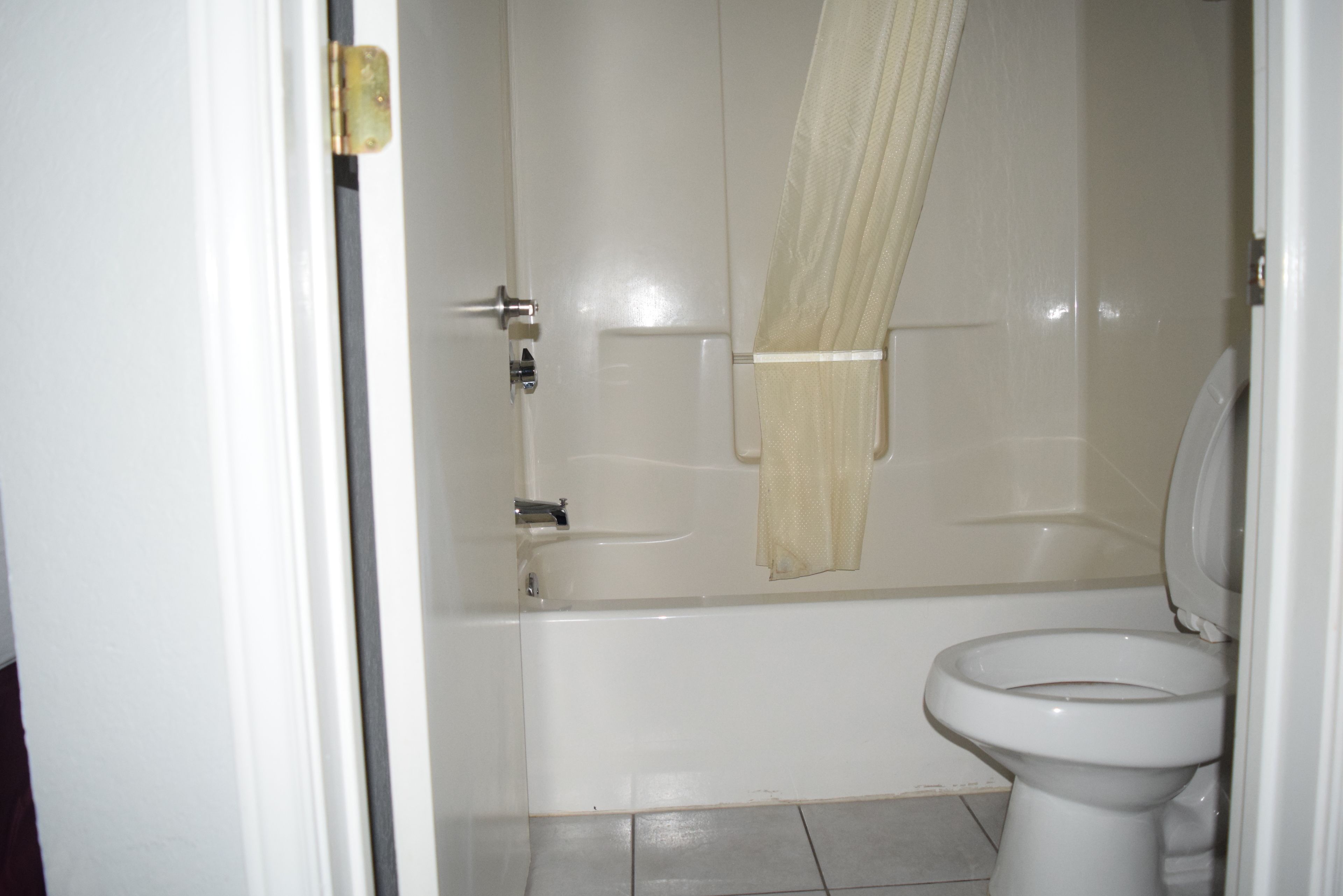 A bathroom with a bathtub, toilet, and a shower curtain.