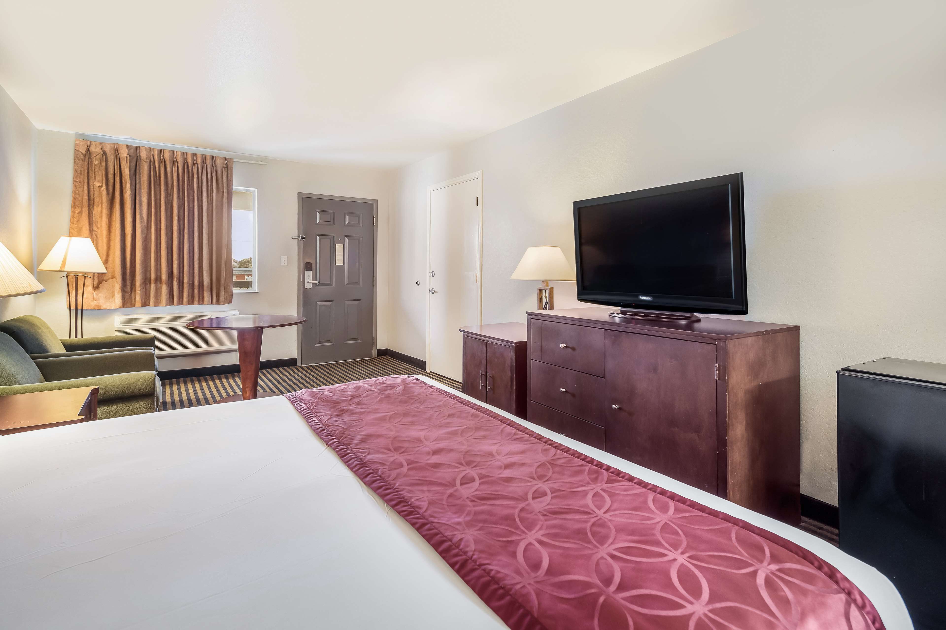 A hotel room with a large bed, a TV, a desk, and a couch.