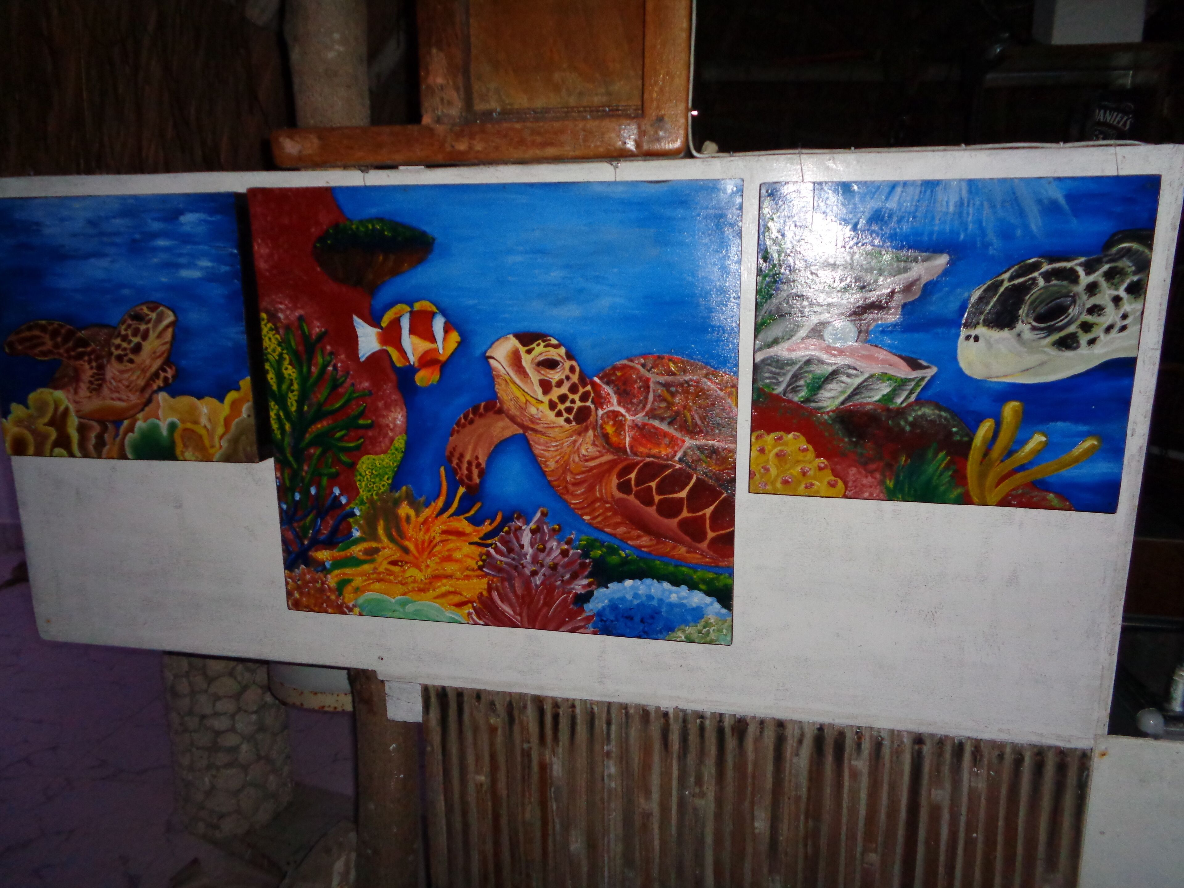 Una pintura de una tortuga terrestre, un pez y una tortuga marina sobre un caballete blanco.