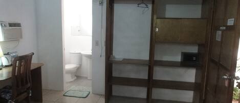 Une petite pièce, de taille modeste, comprenant un meuble en bois, une chaise, une table et des toilettes.