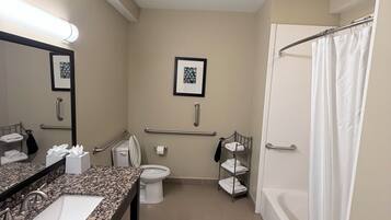 A modern bathroom with a granite countertop sink, a toilet, a bathtub, and a shower curtain.