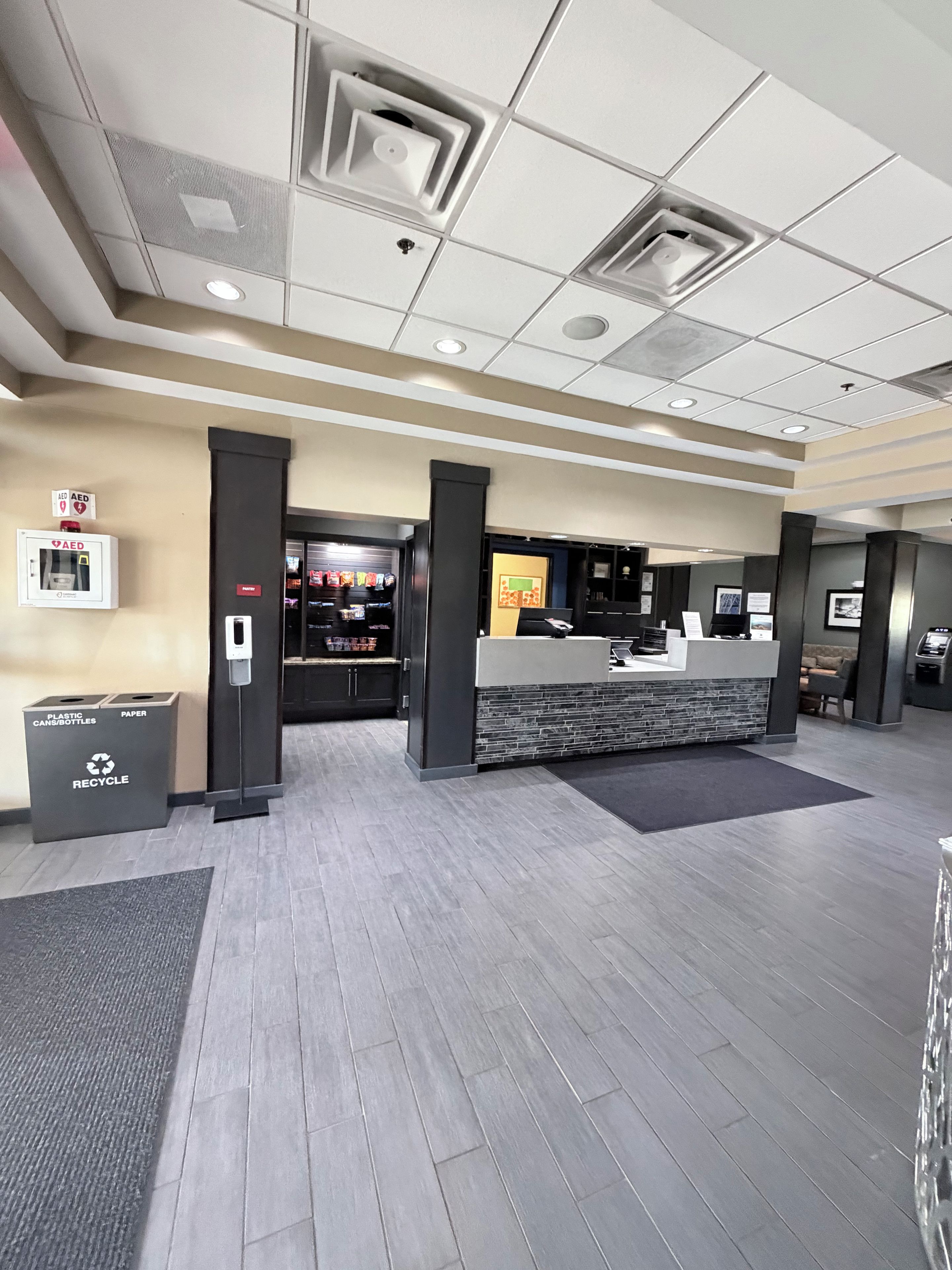 A reception area with a check-in counter, a recycling bin, and an AED emergency station.