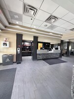 Zona de recepción con mostrador de check-in, contenedor de reciclaje y estación de desfibrilador.