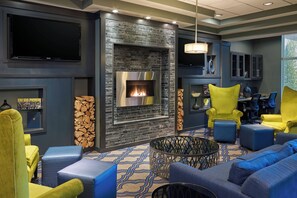 A modern living room with a fireplace, comfortable seating, and a flat-screen TV. - Four Points by Sheraton Williston (Williston)