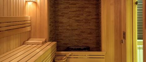 Una sauna con bancos de madera y una pared de piedra.