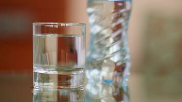 A glass of water and a water bottle with a tag on a table.