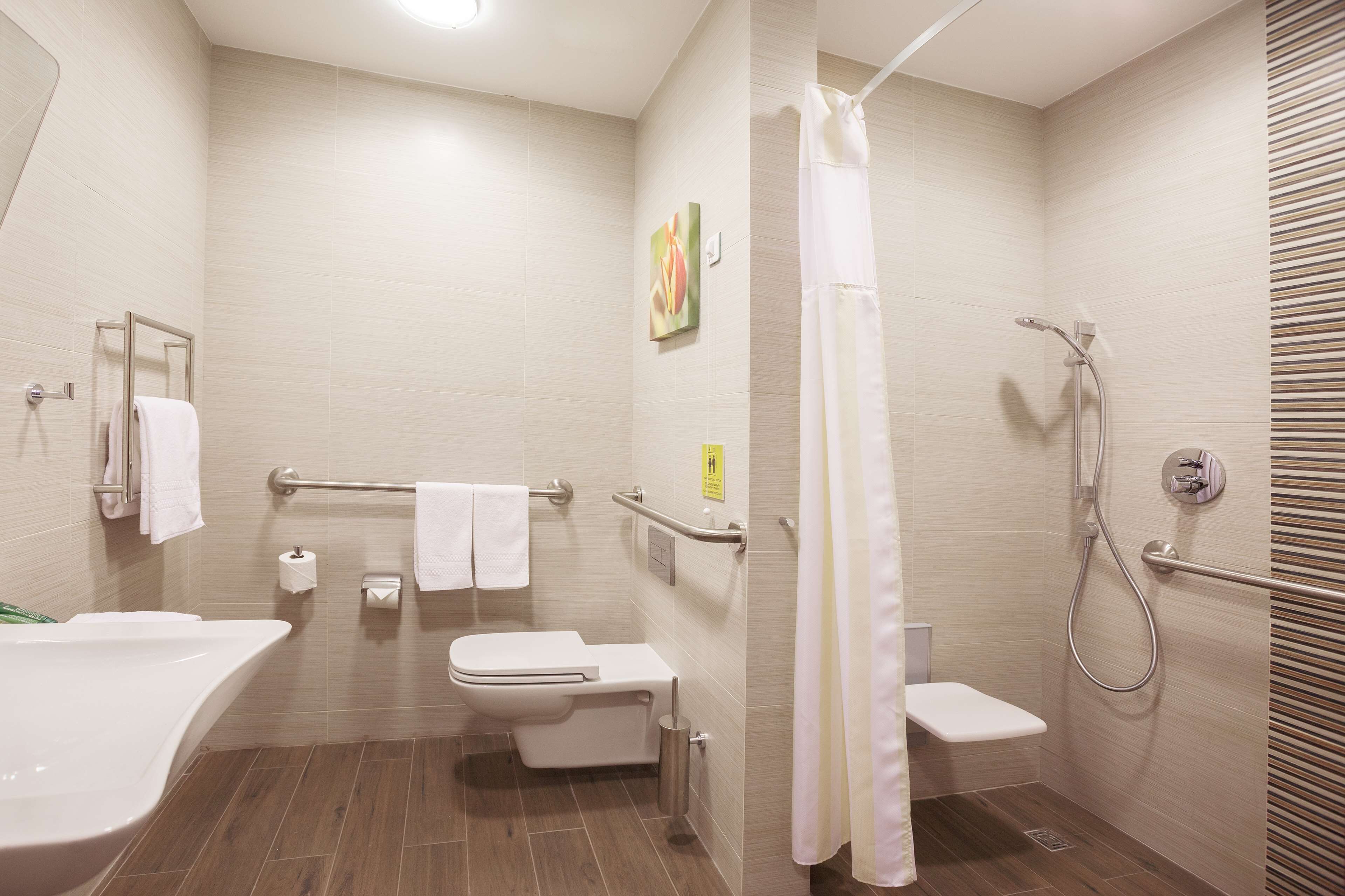Un baño moderno con bañera, inodoro, ducha y barras de apoyo.