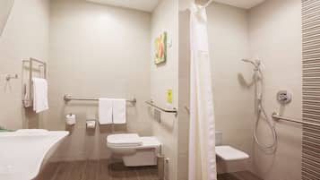 Un baño moderno con bañera, inodoro, ducha y barras de apoyo.