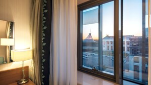 A hotel room with a large window, a bedside lamp, and a view of a cityscape. - Hilton Garden Inn Astana (Astana)