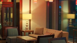 A modern lobby with a sofa, armchairs, and a table. There are pendant lights and a lamp on a side table. - Hilton Garden Inn Astana (Astana)