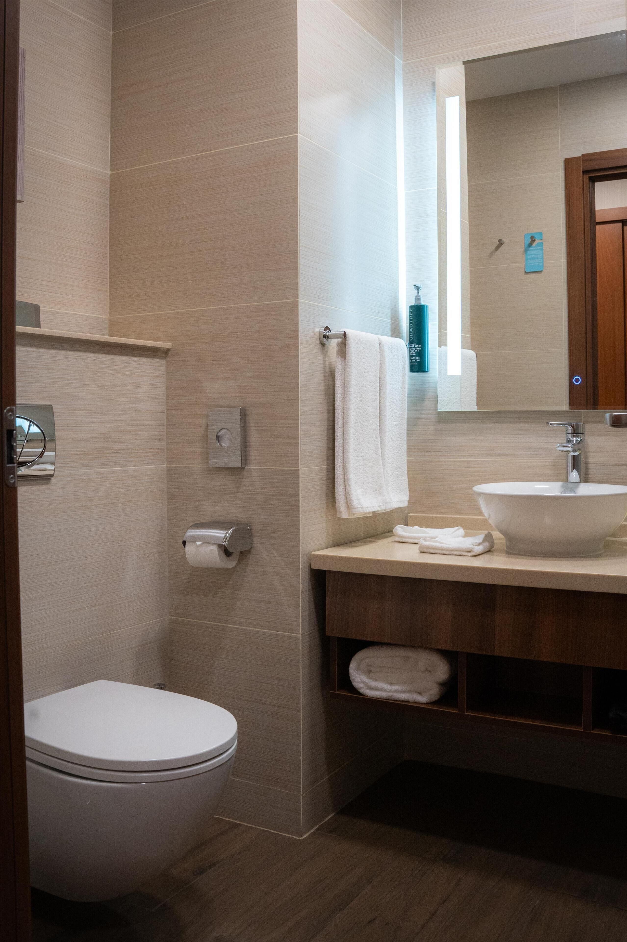 Een moderne badkamer met toilet, wastafel en spiegel.
