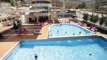 Una piscina techada, una piscina al aire libre de temporada, sombrillas