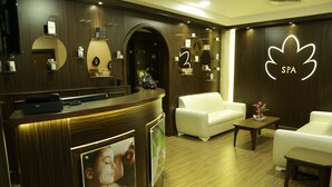 A spa reception area with a reception desk, white sofas, and a flower vase. - Golden Lili Resort & Spa (Aley)