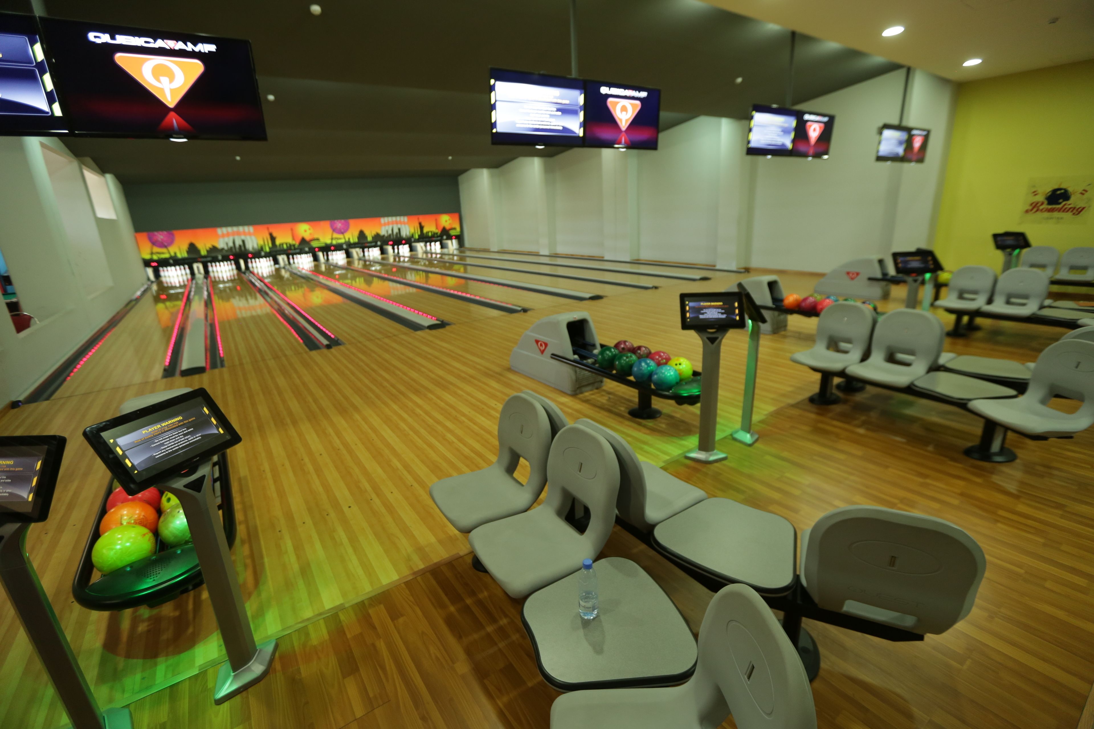 A bowling alley with multiple lanes, seating areas, and digital scoreboards.