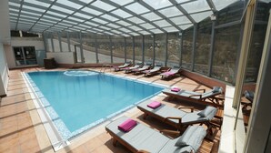 A covered swimming pool with lounge chairs and a view of the surrounding landscape. - Golden Lili Resort & Spa (Aley)
