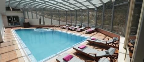 Una piscina cubierta con tumbonas y vistas del paisaje circundante.