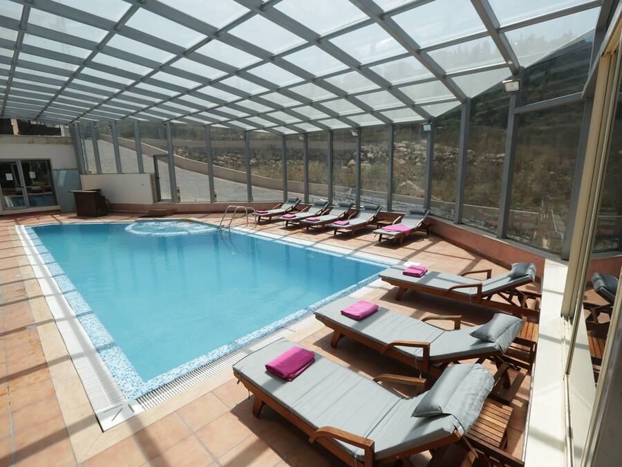 Una piscina cubierta con tumbonas y vistas del paisaje circundante.