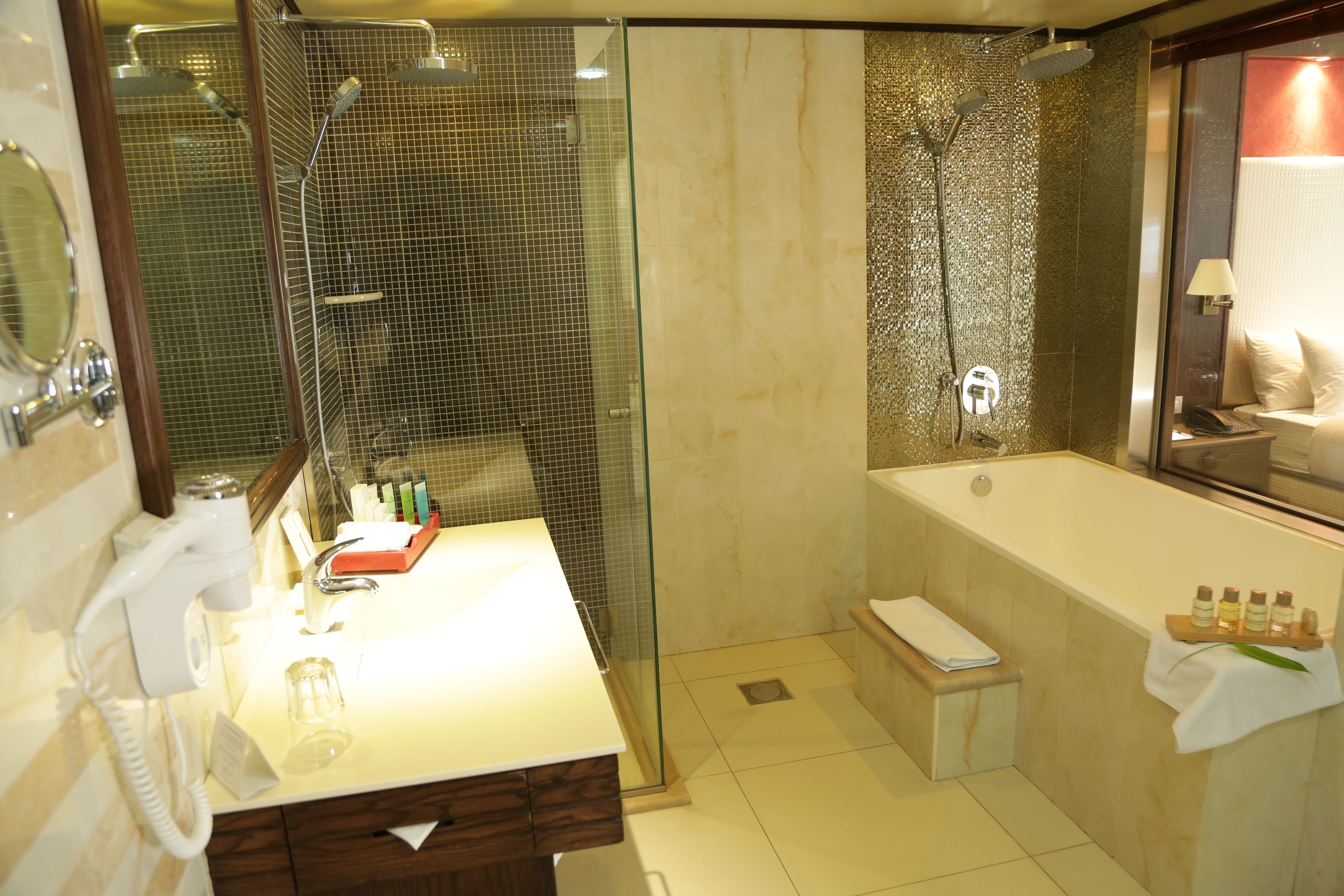 A modern bathroom with a glass shower enclosure, a separate bathtub, and a vanity with a mirror and telephone.