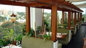 A restaurant with outdoor seating, wooden beams, and potted plants. - Aurick Boutique Hotel (Bengaluru)