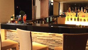 A bar area with wicker chairs, a stone wall, and a variety of liquor bottles. - Aurick Boutique Hotel (Bengaluru)