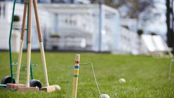 A cricket set on a grassy field with a goal post and stumps.