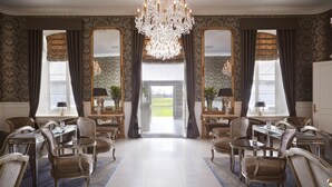 Une salle à manger élégante, agrémentée d’un lustre, de grandes fenêtres et de meubles classiques.