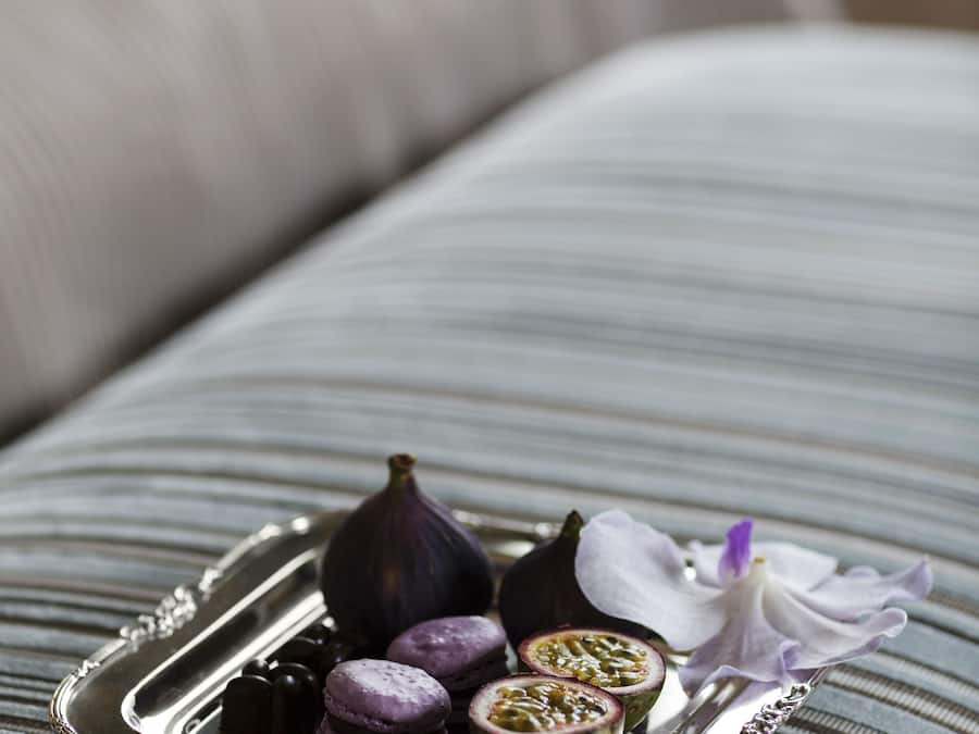 Un plateau contenant des macarons, des figues et une fleur, posé sur une surface en tissu à rayures.