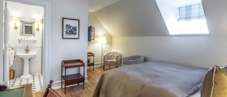 Un dormitorio con una cama grande, un tragaluz, una tocador con espejo y una silla.