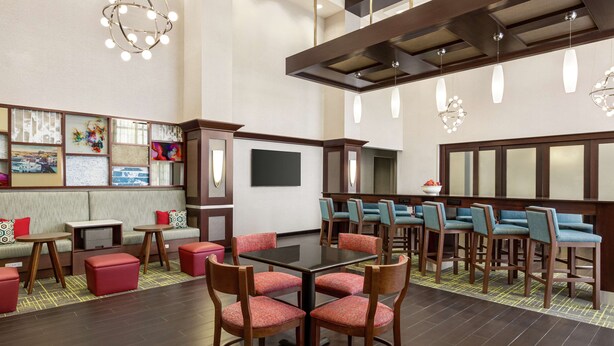 A modern hotel lobby with a central seating area, a reception desk, and artwork on the walls. - Hampton Inn & Suites York South (York)