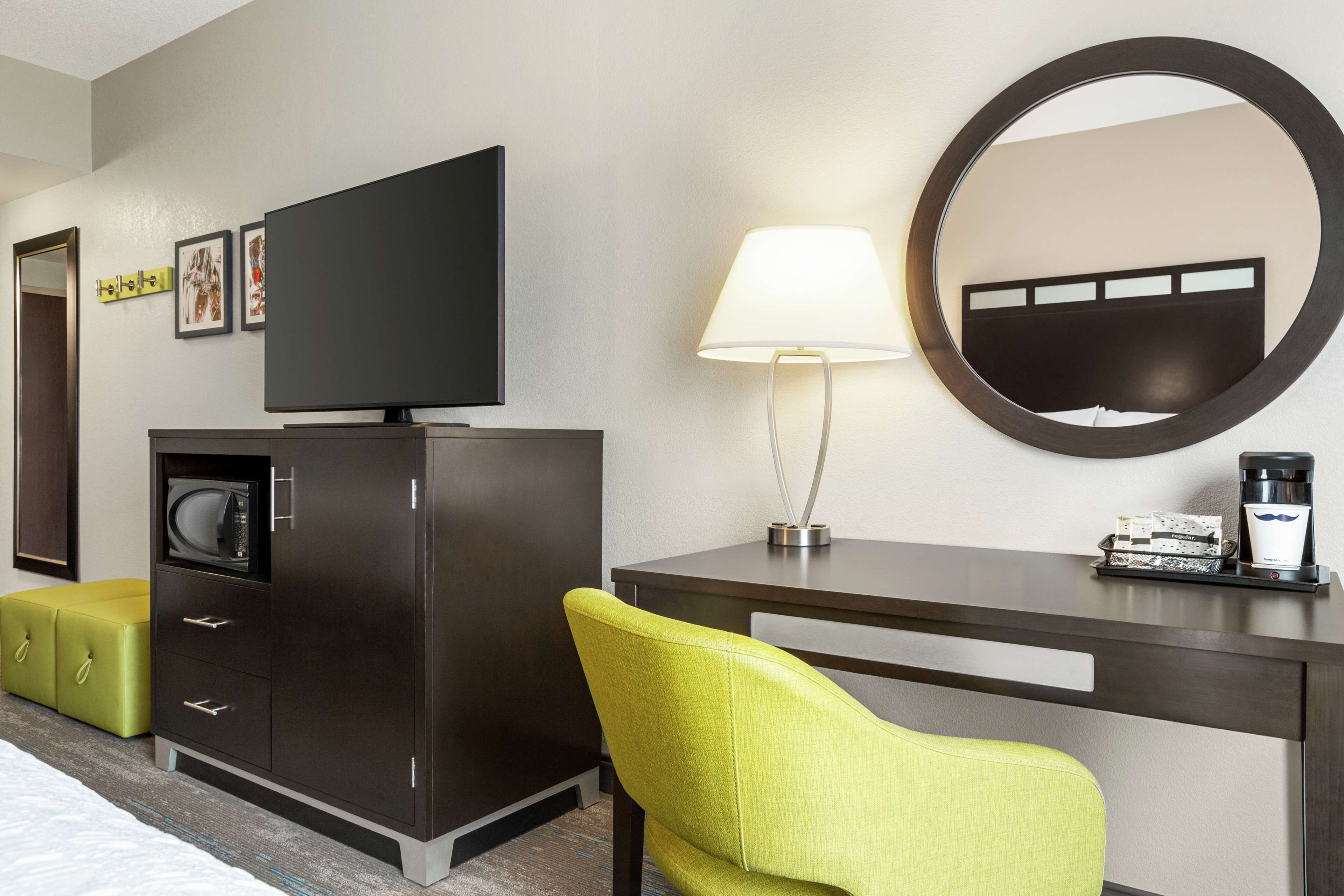 A hotel room with a bed, a desk with a lamp, a television, a microwave, and a coffee maker.