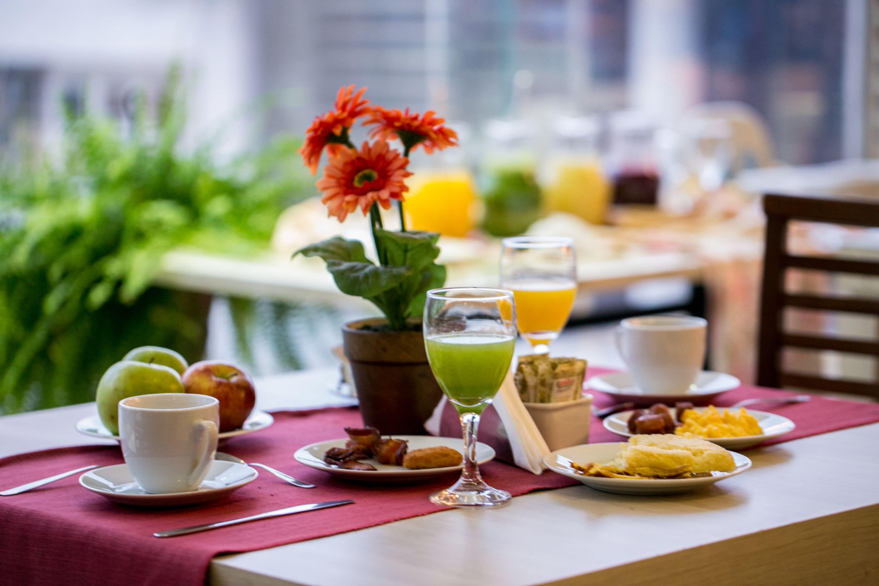 Una mesa de desayuno con platos de comida, un vaso de jugo verde y una taza de café.